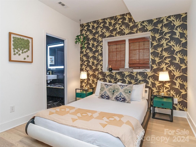 bedroom with ensuite bathroom and hardwood / wood-style floors