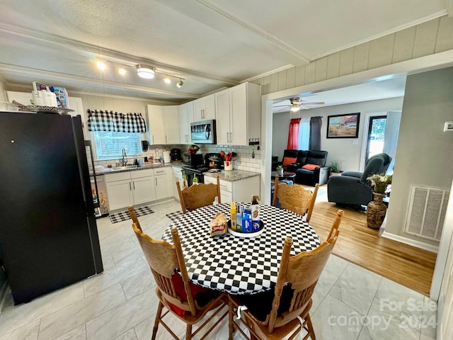 dining area featuring a textured ceiling, ornamental molding, sink, ceiling fan, and light wood-type flooring