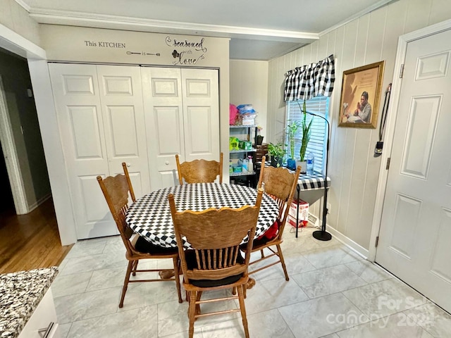 dining space featuring crown molding and wood walls