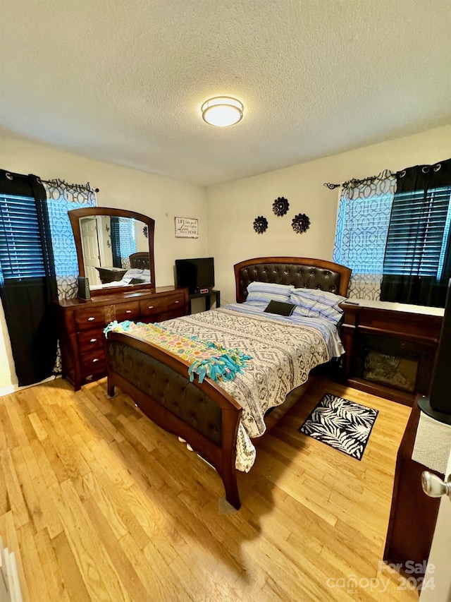 bedroom with a textured ceiling and light hardwood / wood-style floors