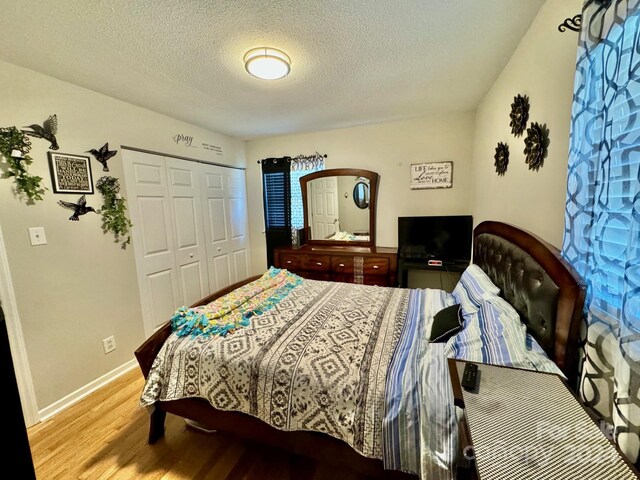 bedroom featuring a closet, wood-type flooring, and a textured ceiling