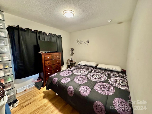 bedroom featuring a textured ceiling and light hardwood / wood-style floors