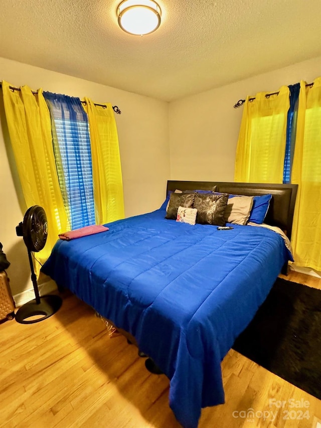 bedroom with a textured ceiling and hardwood / wood-style flooring