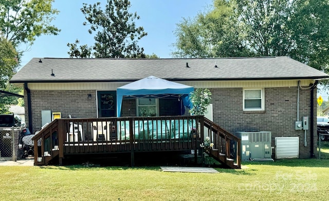 rear view of house featuring central AC, a lawn, and a wooden deck