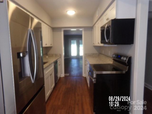 kitchen with white cabinets, dark hardwood / wood-style floors, light stone countertops, and stainless steel appliances