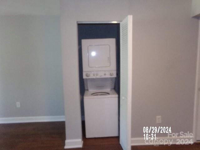 laundry room featuring dark hardwood / wood-style flooring and stacked washer and clothes dryer