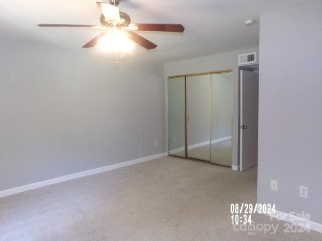 unfurnished bedroom with a closet, ceiling fan, and light colored carpet