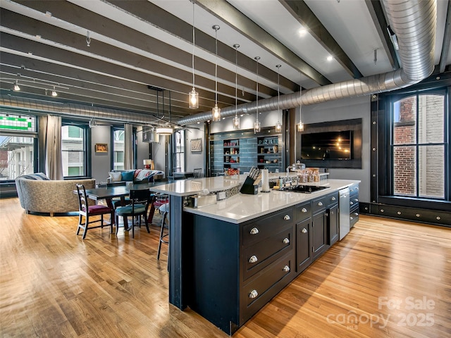 kitchen featuring open floor plan, light countertops, light wood finished floors, and a sink