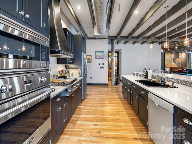 kitchen with a sink, light wood-style floors, appliances with stainless steel finishes, decorative backsplash, and custom range hood