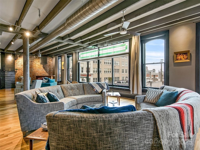 living room featuring beam ceiling, ceiling fan, and wood finished floors