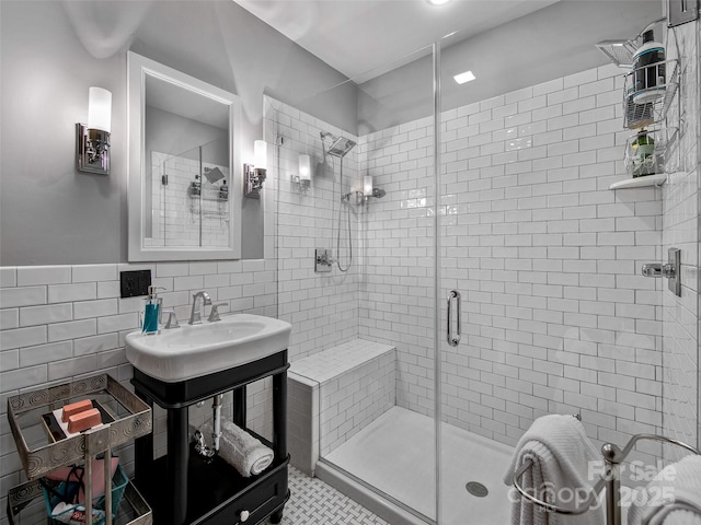 bathroom with a sink, a shower stall, and tile walls