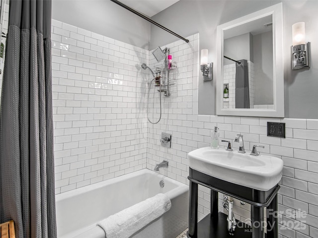 bathroom with a sink, tile walls, and shower / bathtub combination with curtain