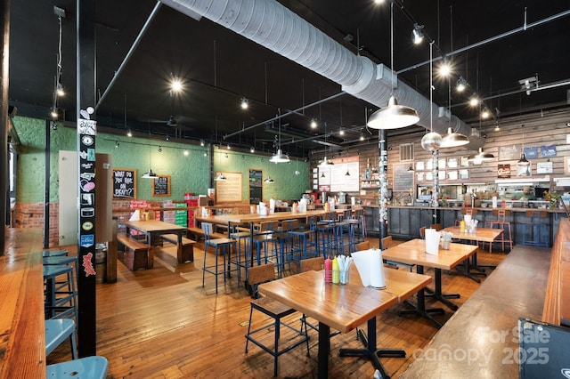 dining area featuring wood-type flooring, a high ceiling, visible vents, and track lighting