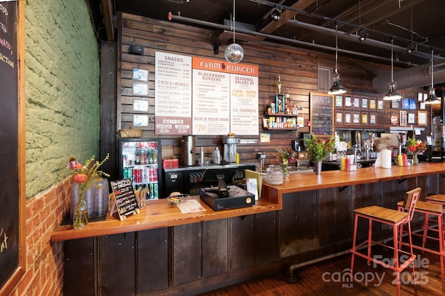 bar featuring brick wall, a bar, and wood finished floors