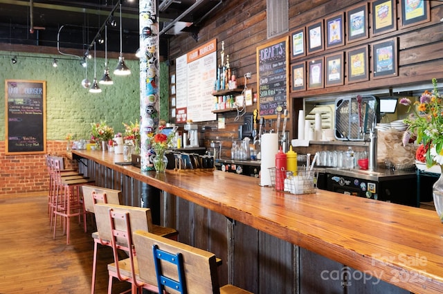 bar with a dry bar, brick wall, and wood finished floors