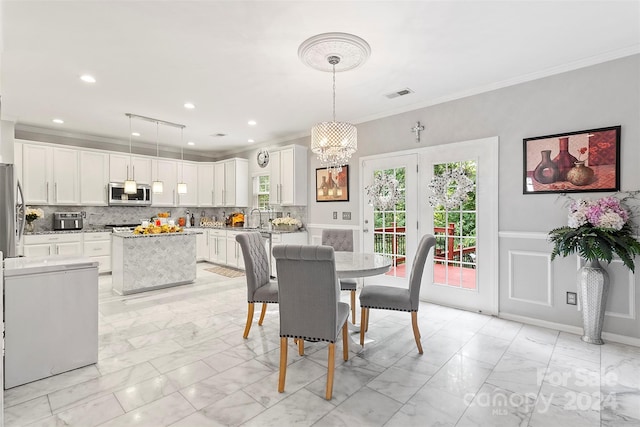 dining space with crown molding, a chandelier, and sink