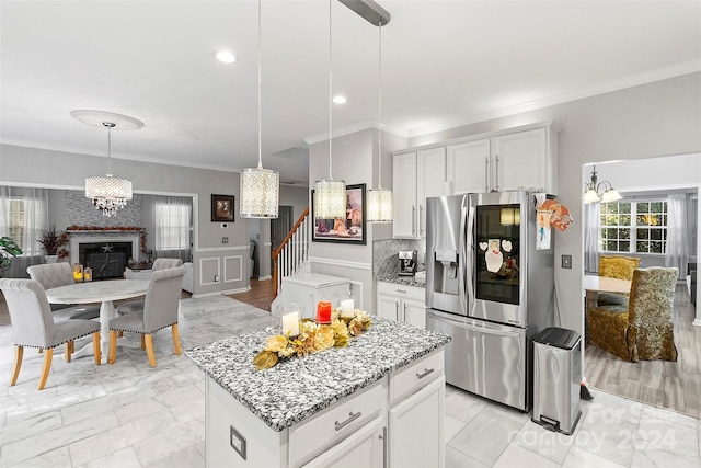 kitchen with a kitchen island, stainless steel fridge with ice dispenser, crown molding, light wood-type flooring, and white cabinets