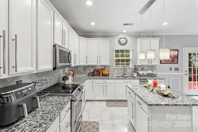 kitchen with hanging light fixtures, light stone counters, stainless steel appliances, and white cabinetry