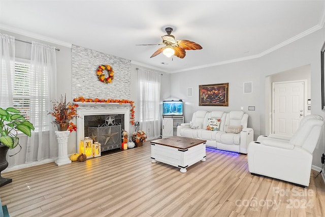 living room featuring ceiling fan, ornamental molding, light wood-type flooring, and a fireplace