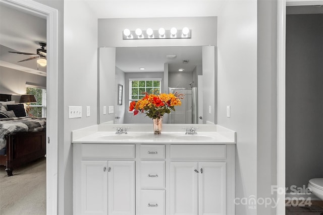 bathroom featuring a shower with door, vanity, toilet, and ceiling fan