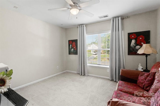 living area featuring carpet flooring, baseboards, ceiling fan, and visible vents