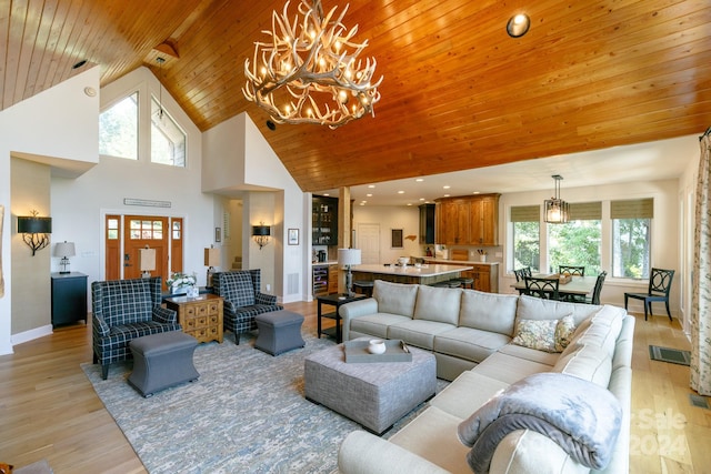 living room featuring high vaulted ceiling, a wealth of natural light, light hardwood / wood-style floors, and a chandelier