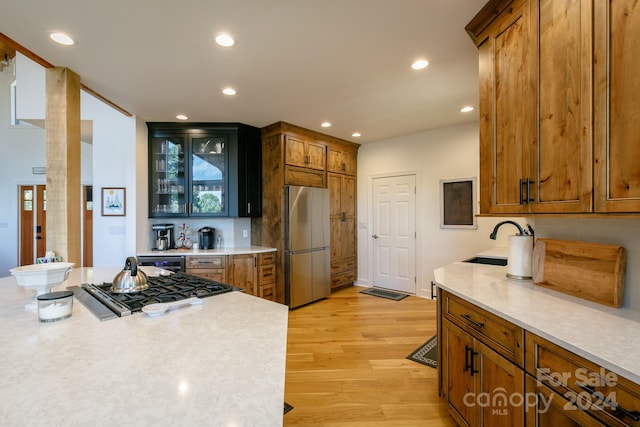 kitchen featuring appliances with stainless steel finishes, tasteful backsplash, sink, and light hardwood / wood-style floors