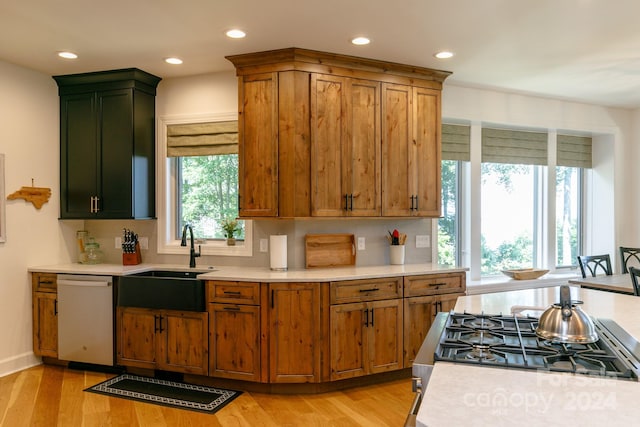 kitchen with appliances with stainless steel finishes, a wealth of natural light, backsplash, and light hardwood / wood-style floors