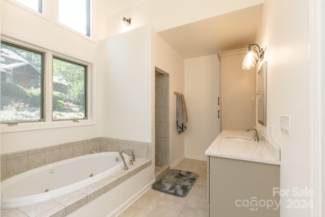 bathroom featuring tiled tub, vanity, and tile patterned floors