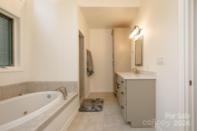 bathroom featuring tile patterned flooring, tiled tub, and vanity