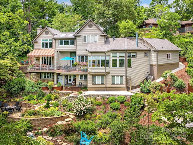 back of property featuring a balcony, a patio area, and central AC