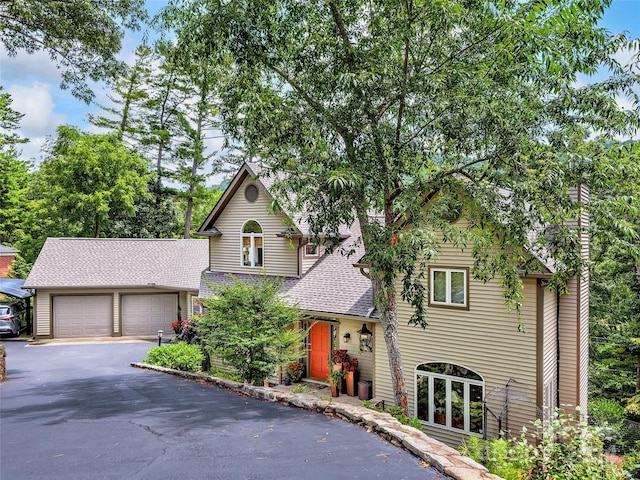 traditional-style home featuring a garage, driveway, and a shingled roof