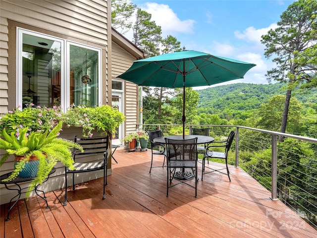 wooden deck with outdoor dining space and a wooded view