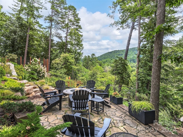 view of patio with a forest view and an outdoor fire pit