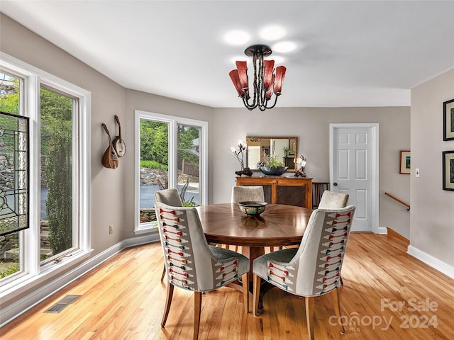 dining space featuring visible vents, light wood-style flooring, baseboards, and an inviting chandelier