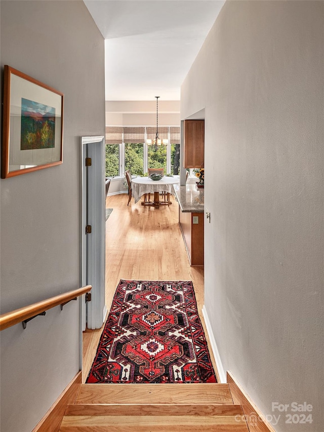 hall featuring light hardwood / wood-style flooring and a chandelier