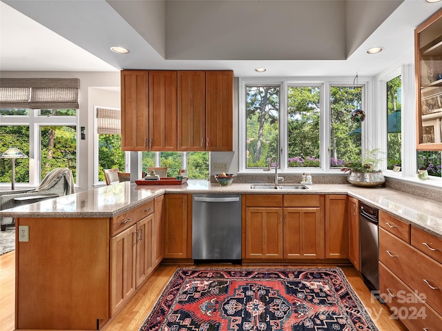 kitchen featuring dishwasher, light hardwood / wood-style flooring, light stone counters, plenty of natural light, and kitchen peninsula