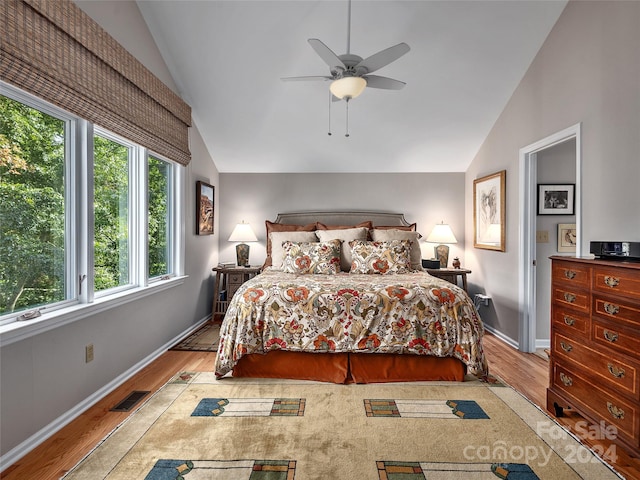 bedroom featuring lofted ceiling, ceiling fan, light wood-type flooring, and multiple windows