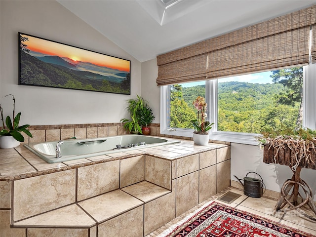 bathroom featuring vaulted ceiling, a relaxing tiled tub, and tile patterned floors