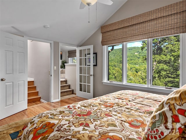 bedroom featuring light wood-type flooring, ceiling fan, lofted ceiling, and ensuite bathroom