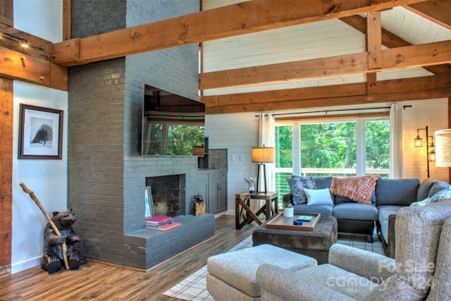 living room with hardwood / wood-style floors, beam ceiling, high vaulted ceiling, a brick fireplace, and wooden walls