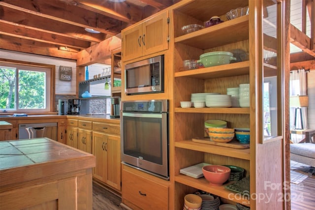 kitchen with appliances with stainless steel finishes, tile countertops, and dark hardwood / wood-style floors