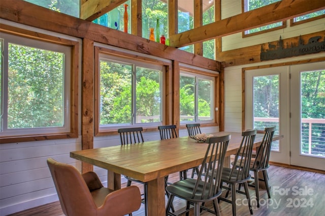 dining space with high vaulted ceiling, hardwood / wood-style floors, and wood walls