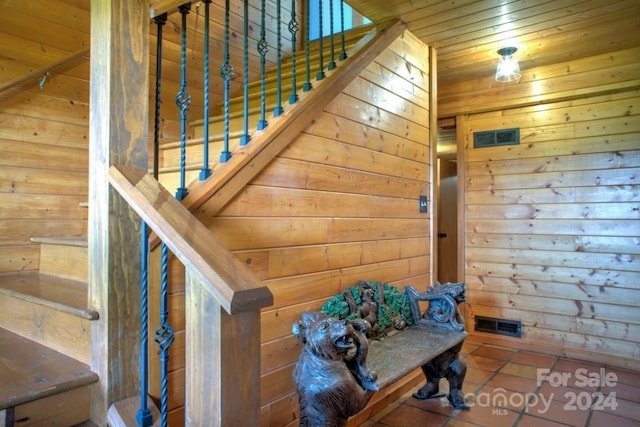 stairway featuring wood walls and wood ceiling