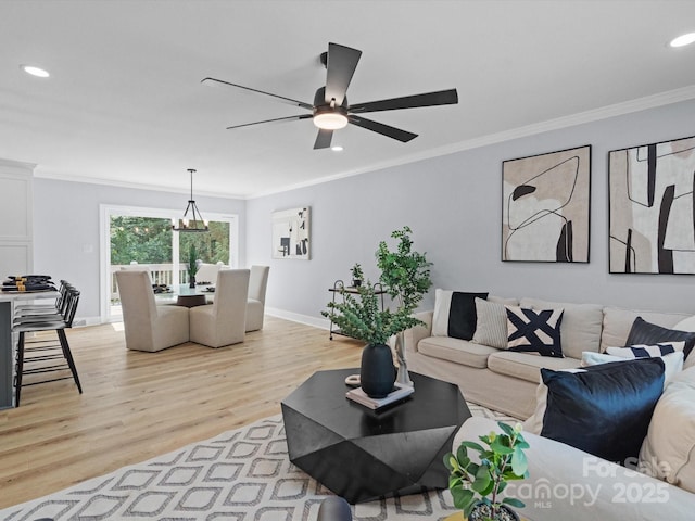 living room featuring light wood-type flooring, ceiling fan with notable chandelier, and ornamental molding