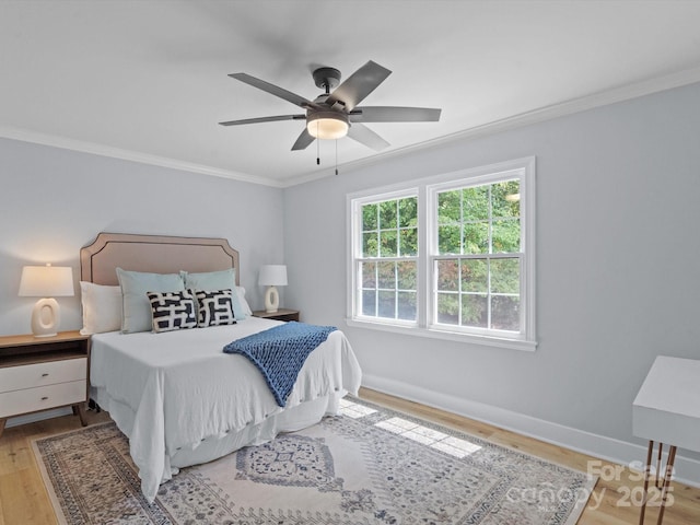 bedroom with light wood-type flooring, ceiling fan, and crown molding