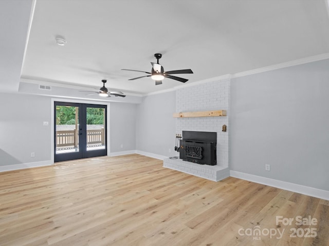 unfurnished living room featuring light hardwood / wood-style floors, ceiling fan, a wood stove, french doors, and crown molding