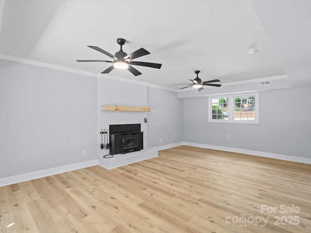 unfurnished living room featuring a brick fireplace, ornamental molding, light hardwood / wood-style flooring, and ceiling fan