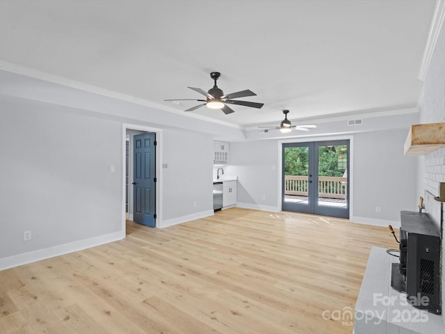 living room featuring ceiling fan, a brick fireplace, french doors, crown molding, and light hardwood / wood-style flooring