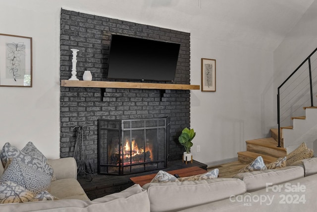 living room with hardwood / wood-style flooring, brick wall, and a brick fireplace